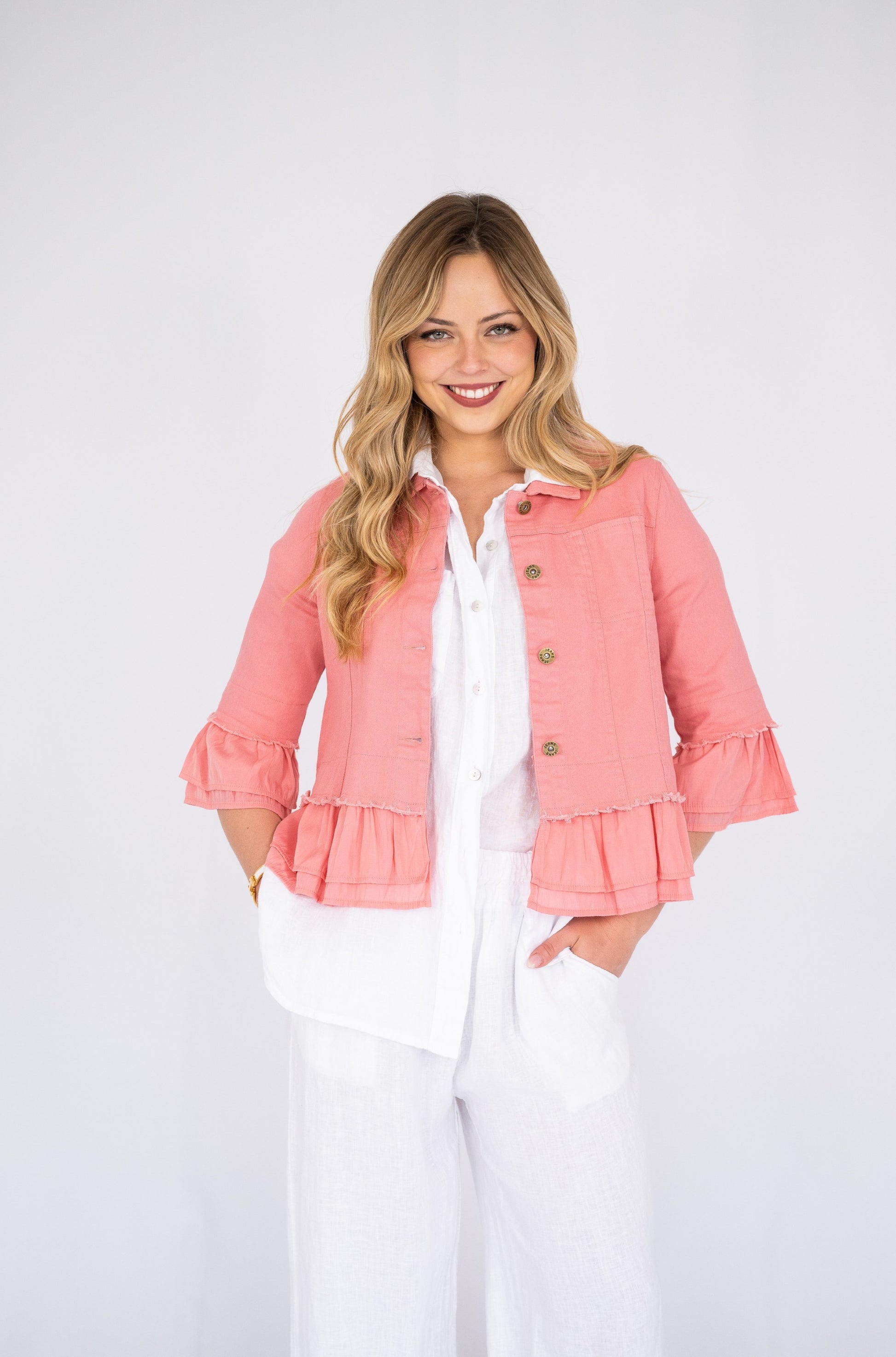 Woman wearing a dusty pink Frill Denim Jacket over a white outfit on a white background