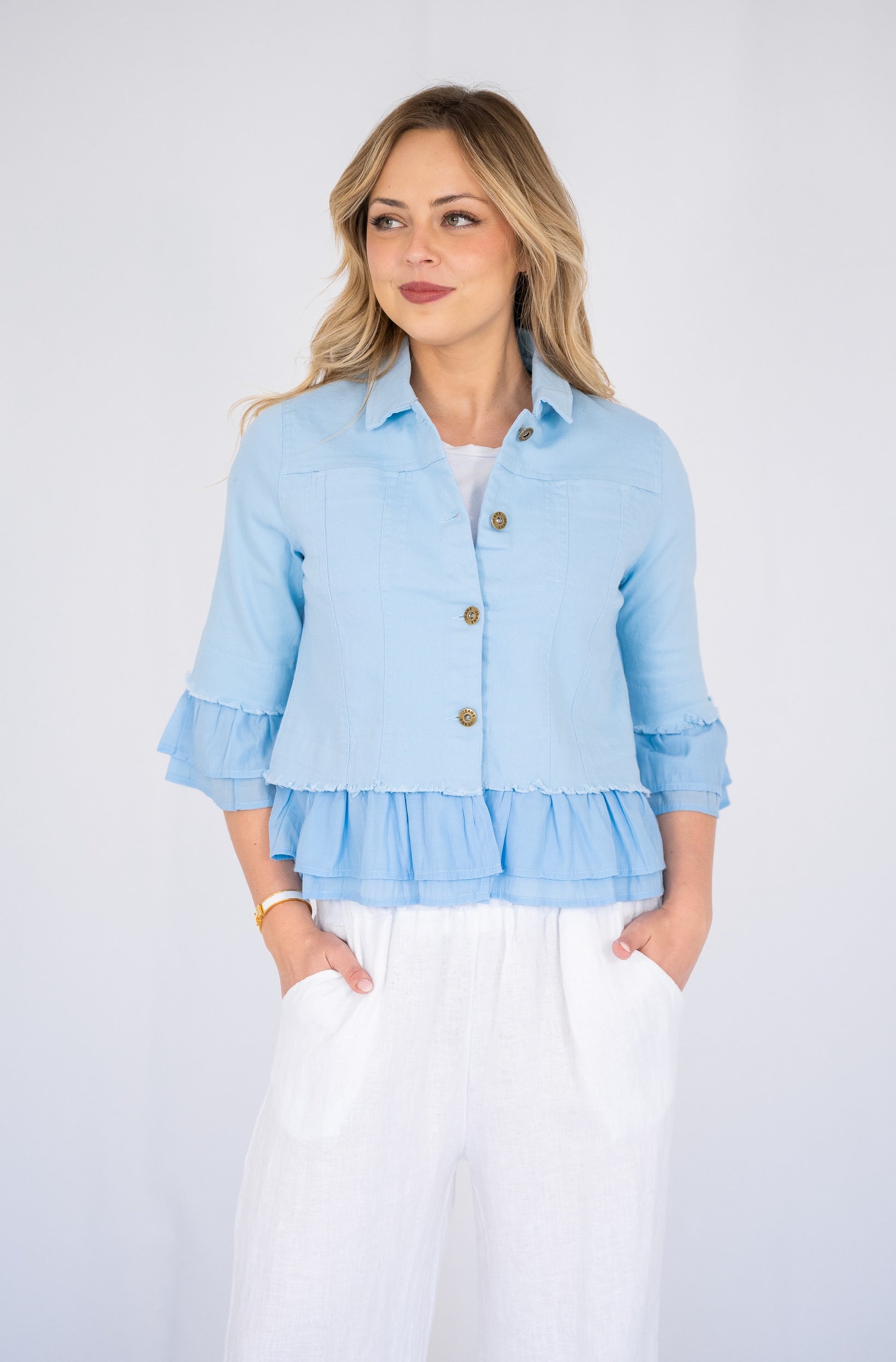 Woman wearing a blue Frill Denim Jacket over a white outfit on a white background