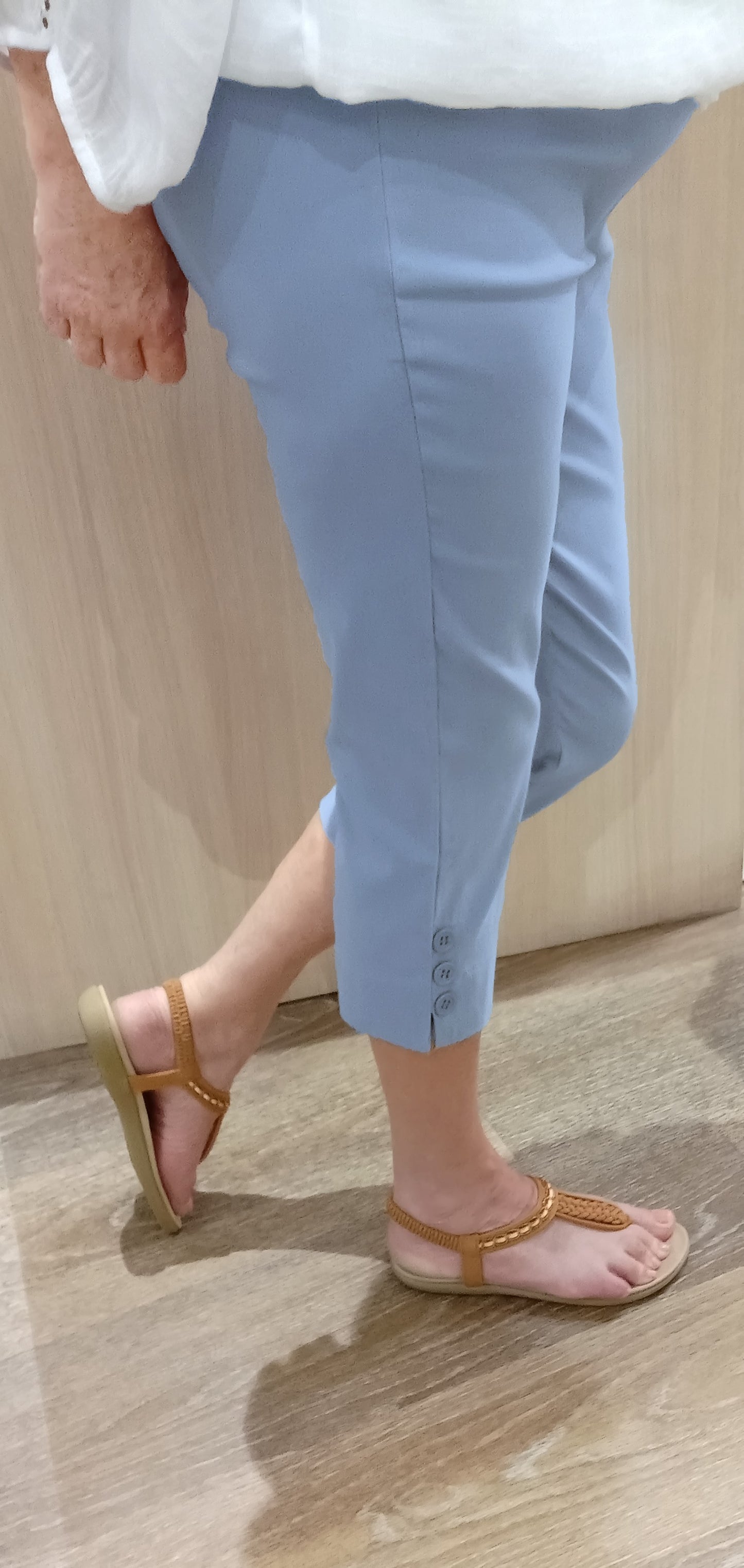 Woman wearing sky SSF Button Pants with a white Gypsy Top and brown thongs near Boo Boo's counter