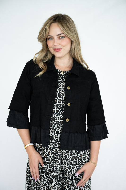 Woman wearing a black Frill Denim Jacket over a leopard print dress on a white background
